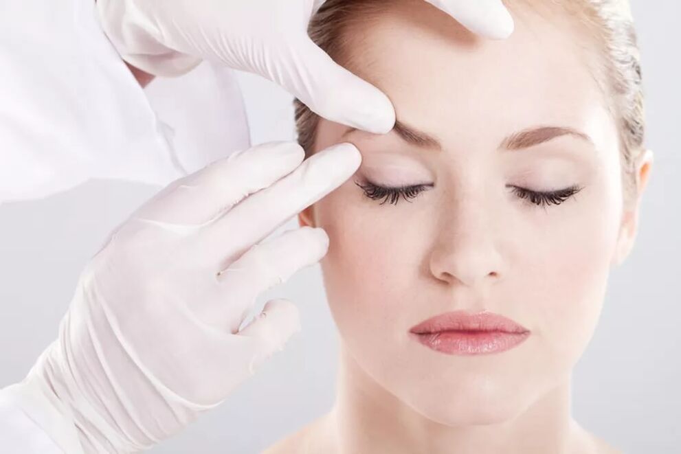 The cosmetologist examines the skin around the eyes
